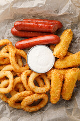 cheese sticks, sausages and onion rings with sauce, close-up