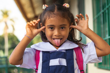 Cheerful young girl in school uniform sticking tongue out and being innocently playful.