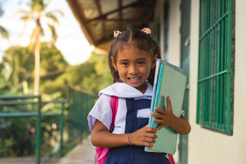 A smiling young student in a uniform, carrying books, exemplifies eagerness and education in a...