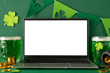 St. Patrick's Day theme: side view photo of laptop open for virtual celebrations, frothy beer mugs,...