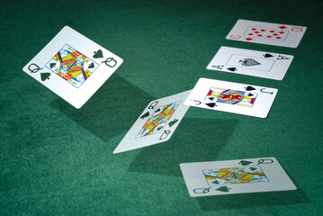 The Queen of spades card flies over the green baize during a poker game.