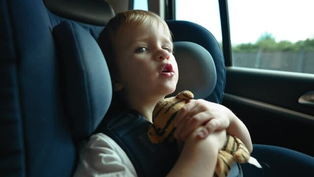 A video capturing the image of a young boy securely seated in a car seat.