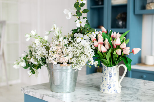 Table At Floristry Workshop Full Of Flowers For Arrangements. Spring Flowers In Vase And Book In Kitchen Table. Bouquet Of Flowers And Plants In Vase At Home. 8 March, Easter, Mother Day. Gardening	
