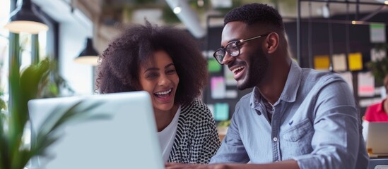 Happy man and woman working together at the office, sharing ideas in a friendly atmosphere using wireless technology for research.