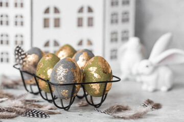 Stylish beautiful Easter eggs with golden potali coating and Easter bunny on a gray background. The concept of happy Easter 2024.
