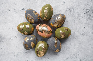 Stylish beautiful Easter eggs with golden potali coating on a gray background. The concept of happy Easter 2024.