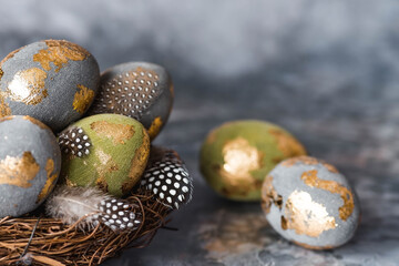 Stylish beautiful Easter eggs with a golden coating of sweat and feathers in a bird's nest of...