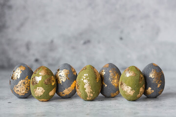 Stylish beautiful Easter eggs with golden potali coating on a gray background. The concept of happy...