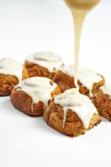 A cinnamon roll is poured with custard and sprinkled with cinnamon on a white background.