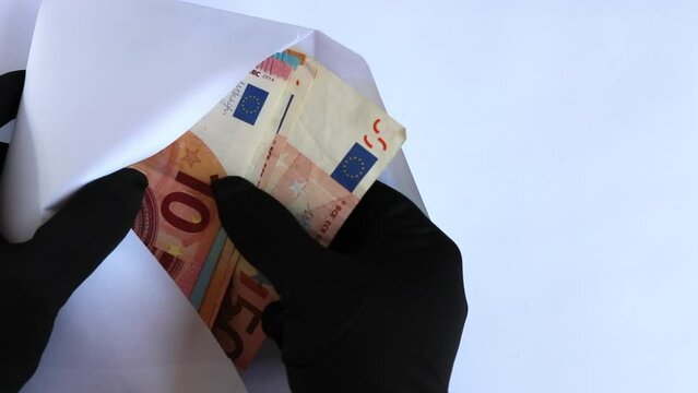 Billetes de euro dentro de un sobre blanco y unas manos con unos guantes negros se lo llevan. concepto de impuestos, delitos.