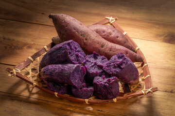 Baked Japanese Roasted Sweet purple yam or purple Potato in wooden plate on wooden table.