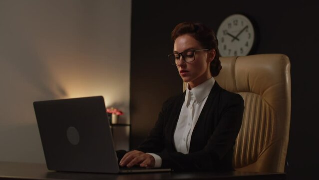 A young woman positive boss sitting on comfortable leather chair in office and using notebook. It specialist lady senior level programmer. Business analytic woman using computer. No paperwork, just