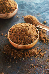 Muscovado brown sugar in wooden  bowl on rusty table  background.