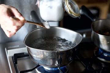 鍋で沸かしたお湯に塩を入れるところ