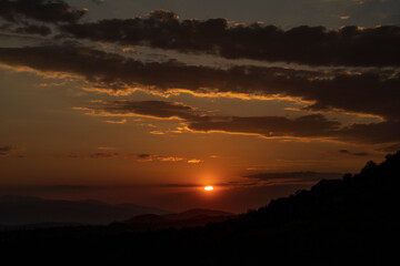 Beautiful sunset in the mountains. Sunset View from the Top of a Mountain. Sunset in strong orange tones in Serbia. The sun falls for horizon, a sunset. Shadows are condensed, beautiful clouds. 