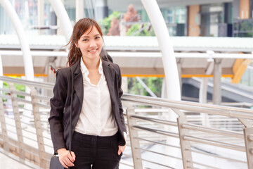 Smiling Asian urban business woman walking outside office