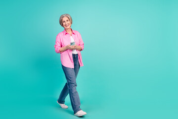 Full size photo of satisfied nice pensioner person walk to empty space with smartphone in hands...