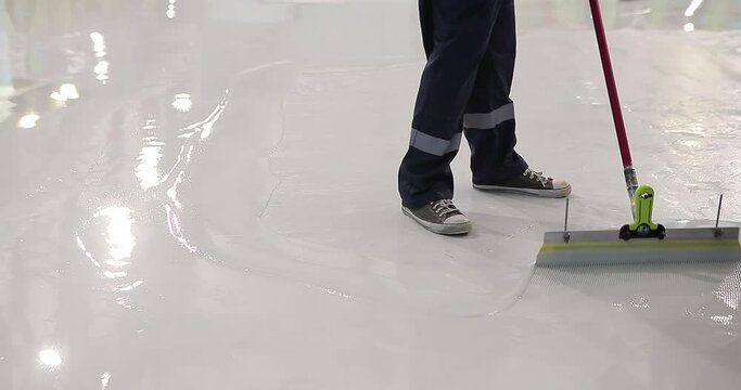 The process of creating polymer floors. A builder distributes resin flooring material evenly using a Scraper Float. A builder is applying polymer floors using Scraper Float.