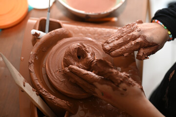 child's hand working clay to make pottery