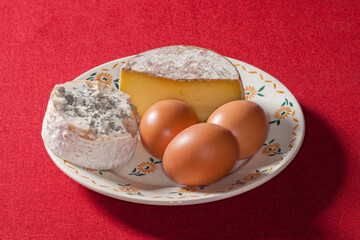 Deux fromages et trois œufs dans une assiette au décor fleuri