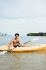 Serenity and Adventure: "Asian Man Enjoying Kayak Fun on a Tropical Beach"
