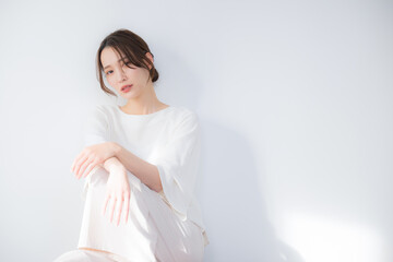 Beautiful Asian (Japanese) woman leaning against a white wall with an ennui look