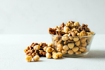 close-up of a glass bowl filled with nuts on a white background