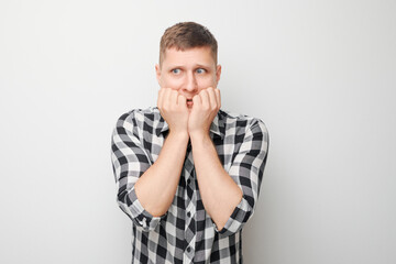 Portrait of guy with sad face worried, biting nails on white background. Nerves, stress,...