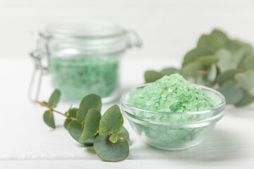Cosmetic sea salt with aroma and eucalyptus extract on a textured wooden background with branches of fresh aromatic eucalyptus.Spa concept. Bath salt. Close-up. Space for text.Body care.copy space