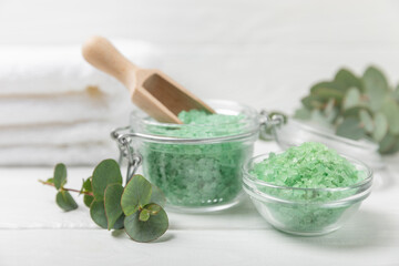Cosmetic sea salt with aroma and eucalyptus extract on a textured wooden background with branches of fresh aromatic eucalyptus.Spa concept. Bath salt. Close-up. Space for text.Body care.copy space