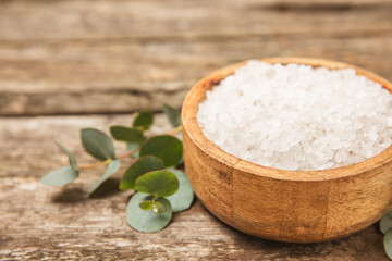 Cosmetic sea salt with aroma and eucalyptus extract on a textured wooden background with branches of fresh aromatic eucalyptus.Spa concept. Bath salt. Close-up. Space for text.Body care.copy space