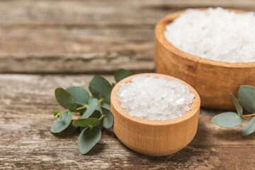 Cosmetic sea salt with aroma and eucalyptus extract on a textured wooden background with branches of fresh aromatic eucalyptus.Spa concept. Bath salt. Close-up. Space for text.Body care.copy space