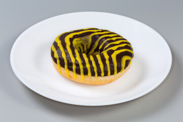 Doughnut with chocolate and yellow glaze, side view close-up