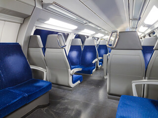 Empty chairs on the upper deck of a public transport train car. Blue chairs, interior lighting, no...