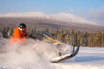 Fotobehang Athlete on a snowmobile moving in the winter forest in the mountains of the Southern Urals © 02irina