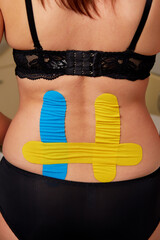 Kinesiology therapeutic taping of lumbar spine of young woman. - obrazy, fototapety, plakaty