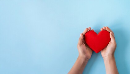 Fototapeta premium Hands holding red heart on blue background. World heart day.