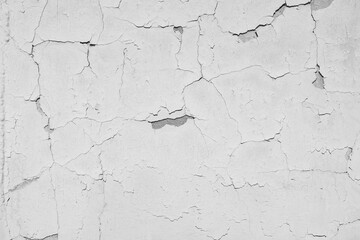 Peeling  white paint on the concrete wall with old cracked flaking paint. Weathered rough painted surface with patterns of cracks and peeling. \ texture for background