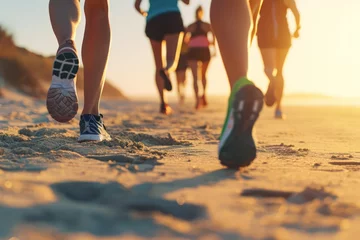 Foto auf Acrylglas Group of runners on a beach at sunset, with a close-up of running shoes in the sand © olga_demina