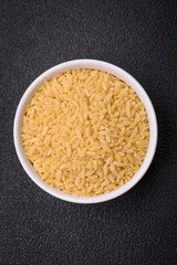 Raw risoni pasta made from durum wheat on a dark concrete background