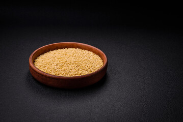 Raw risoni pasta made from durum wheat on a dark concrete background