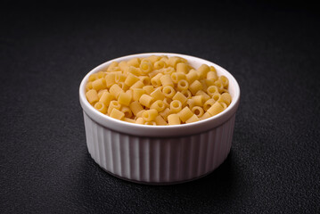 Raw ditali pasta made from durum wheat on a dark concrete background
