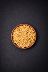 Raw ditali pasta made from durum wheat on a dark concrete background