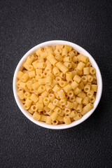 Raw ditali pasta made from durum wheat on a dark concrete background