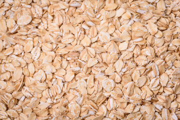 Raw oatmeal flakes in a ceramic bowl on a dark concrete background