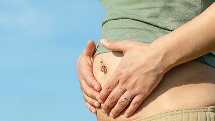 Pregnant woman park with navel piercing two months pregnant outdoors. Navel piercing on pregnant...