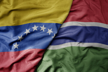 Fototapeta premium big waving national colorful flag of gambia and national flag of venezuela . macro