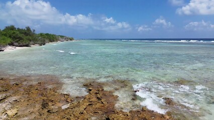 Drone view of paradise islands of the Maldives with coral reefs under the waves of blue the Indian Ocean.