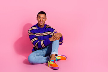 Full body photo of attractive young man sit floor touch knee dressed stylish violet striped clothes isolated on pink color background