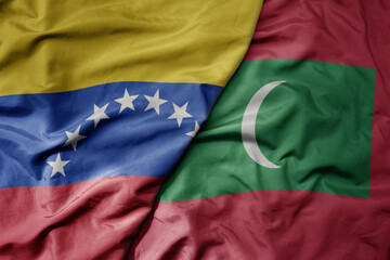 Fototapeta premium big waving national colorful flag of maldives and national flag of venezuela . macro